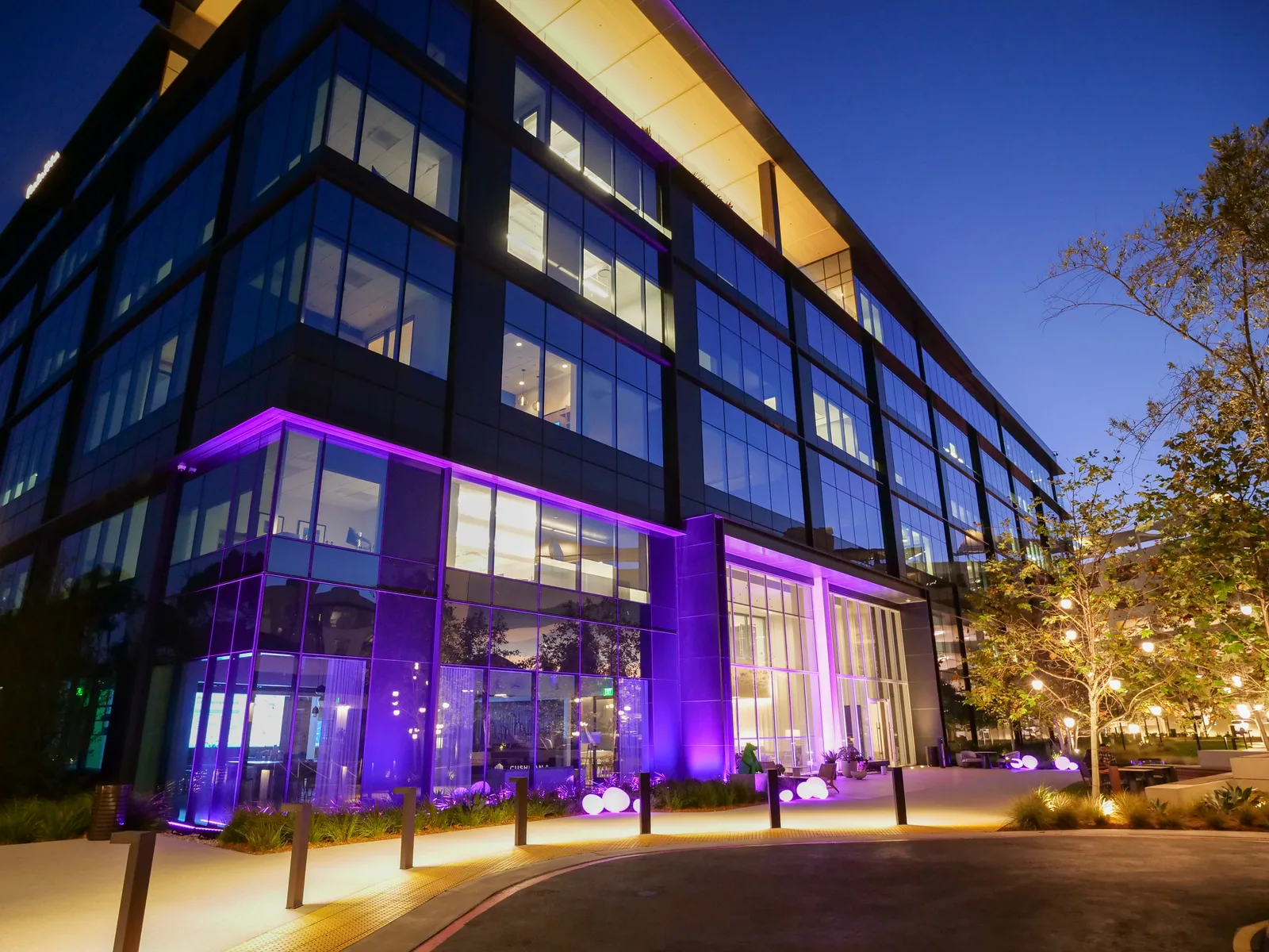 Acadia Pharmaceuticals’ building illuminated in purple lights during the evening, showcasing modern architecture and vibrant ambiance