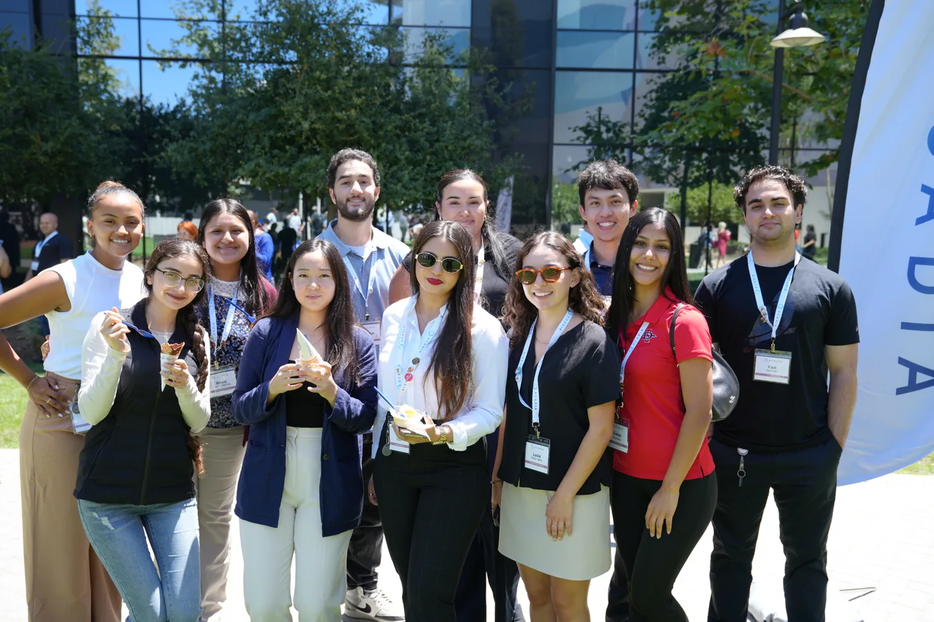 Group of young professionals gathered outdoors, smiling together during a company event, reflecting teamwork and engagement