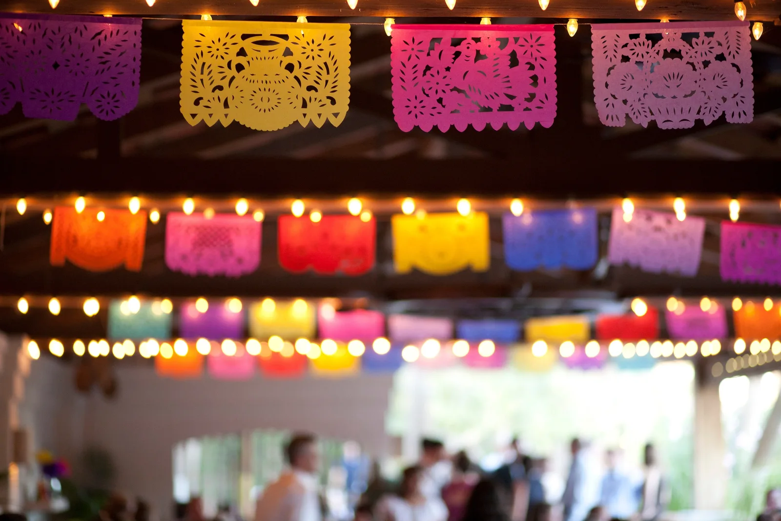 Colorful papel picado banners hanging from the ceiling with string lights, creating a festive atmosphere