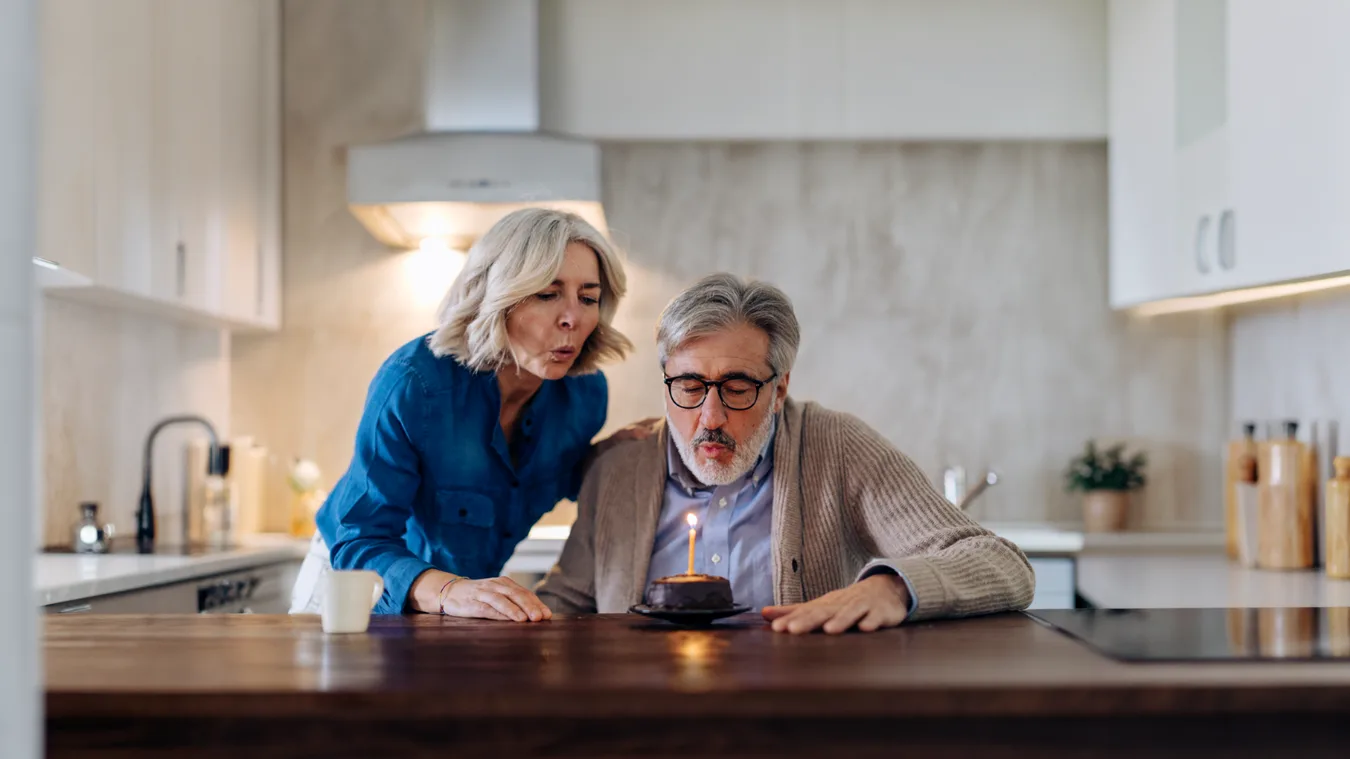 A couple blowing out the candle on a birthday cake
