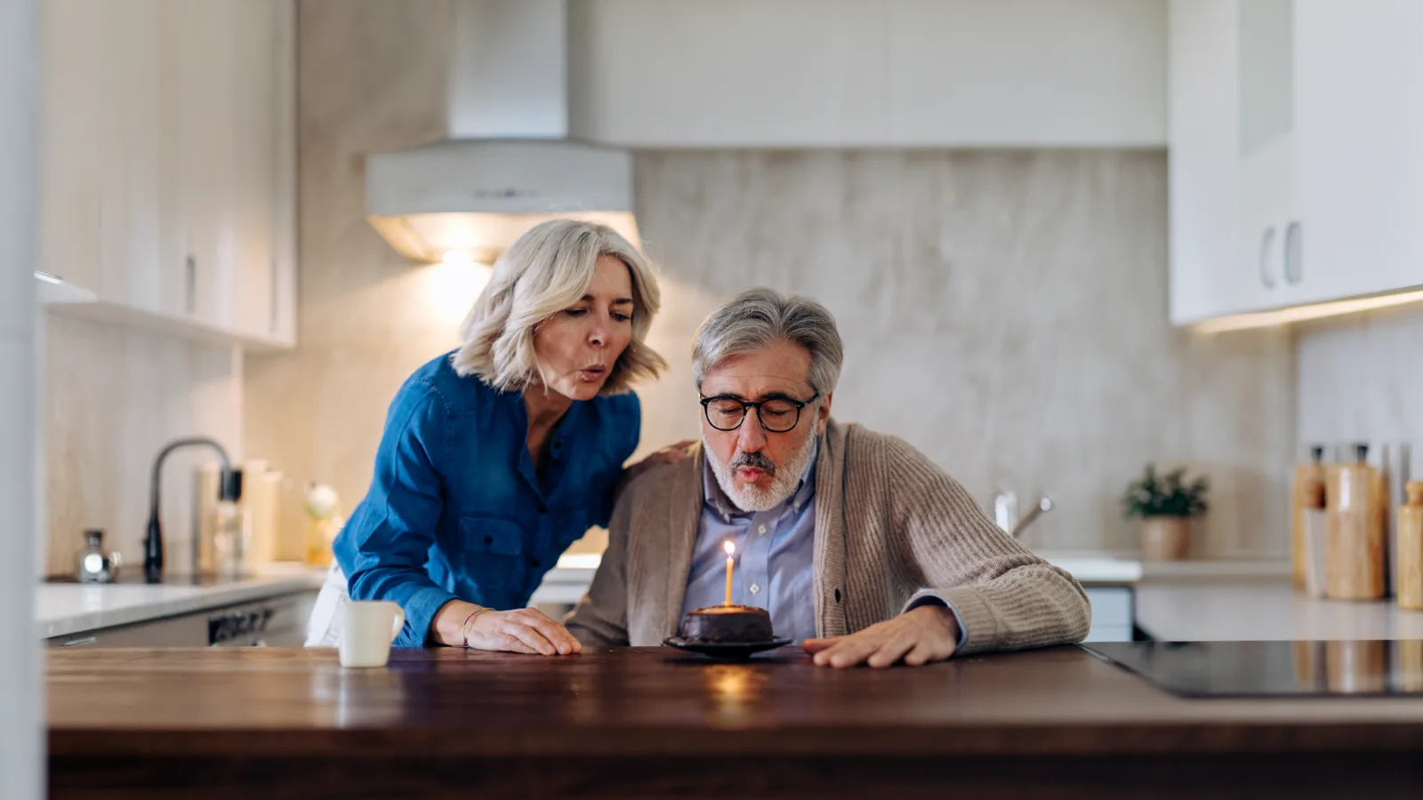 A couple blowing out the candle on a birthday cake
