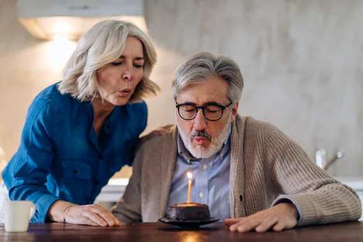 A couple blowing out the candle on a birthday cake