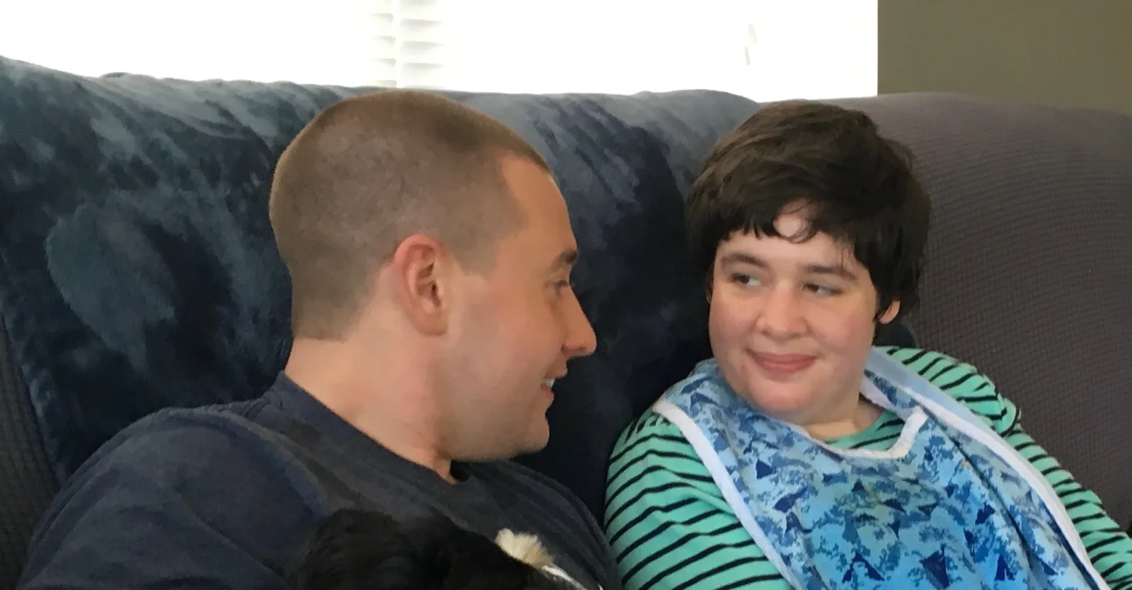 A man and a young woman sharing a warm, close conversation on a couch, symbolizing family connection and support