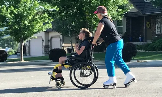 Woman on roller skates pushing a child in a wheelchair