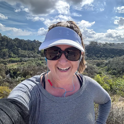 Professional headshot of Michelle, a Rett syndrome advocate, smiling warmly against a scenic outdoor backdrop