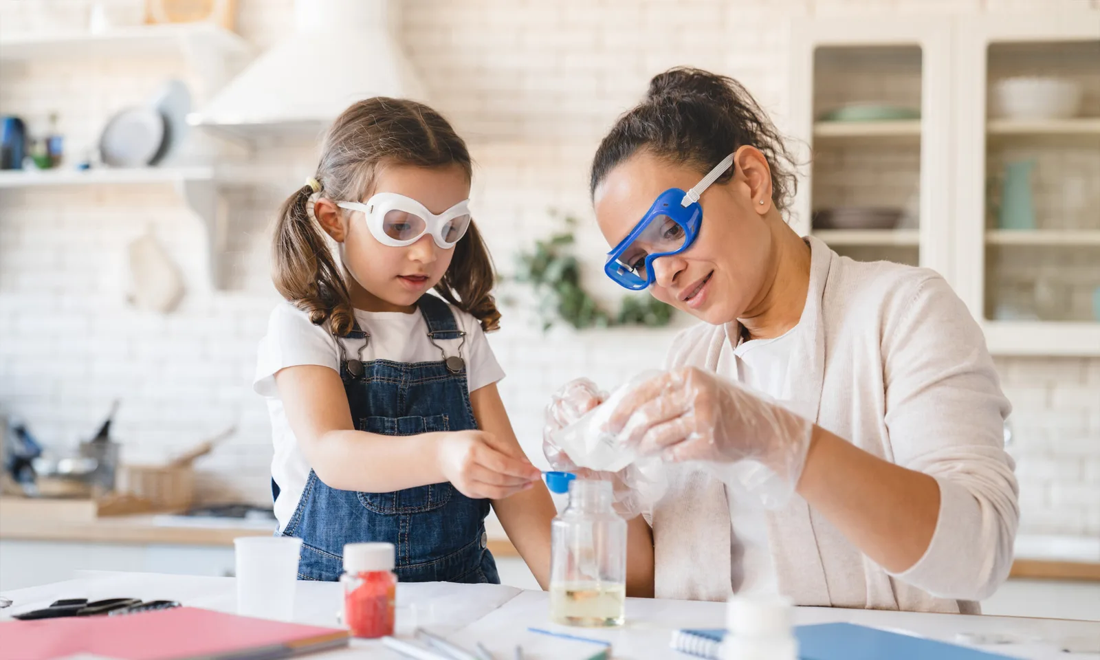 A mother and daughter wearing safety goggles work together on a science experiment at home, symbolizing learning, curiosity, and family bonding